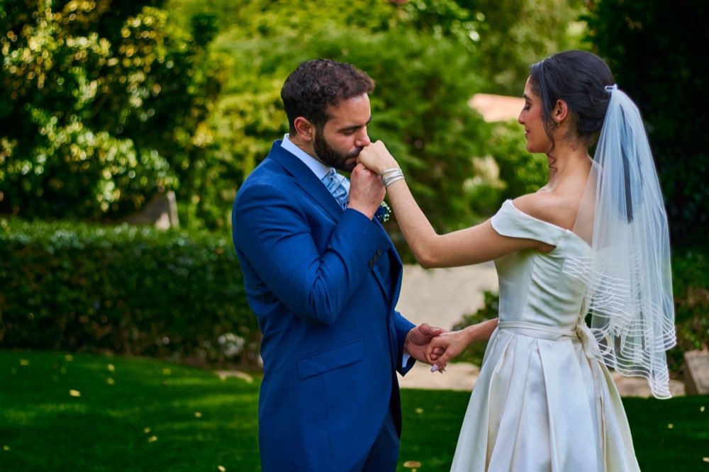 Novio besando la mano de la novia en el jardín