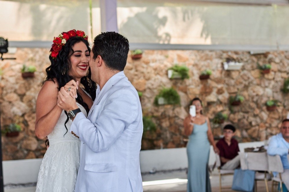 Novios bailando frente a un muro de piedra