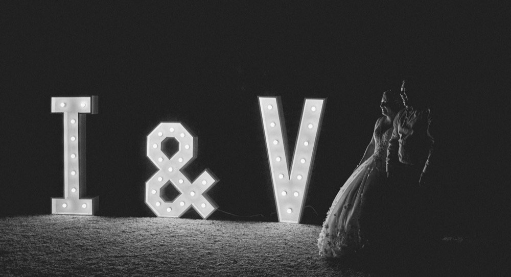 Novios junto a letras gigantes I & V
