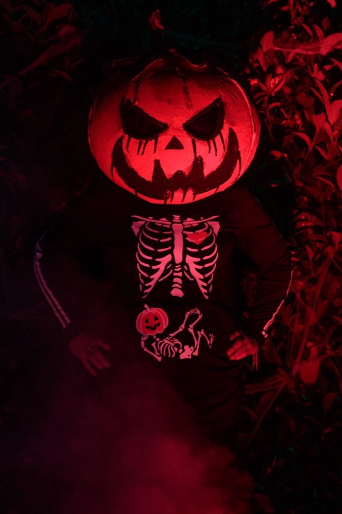 Esqueleto con calabaza iluminada en rojo